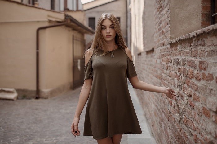 Woman with black nails wearing a dress and necklace outdoors