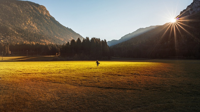 Woman walking in a sunlit mountain field