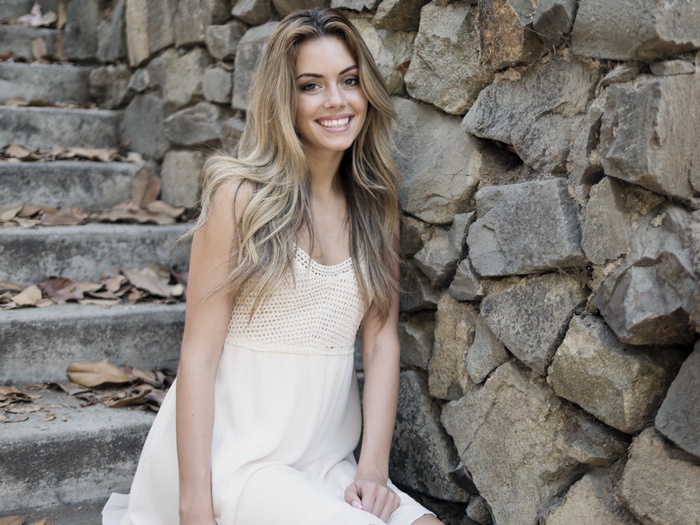 Woman in white dress sitting on stone stairs with fallen leaves