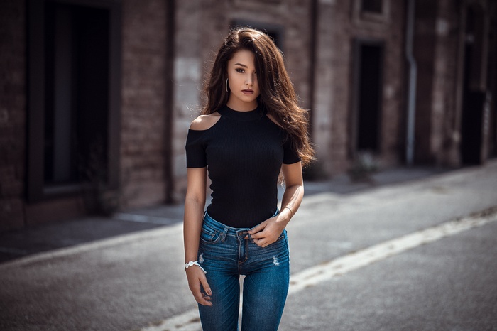 Woman in black top and jeans standing outdoors