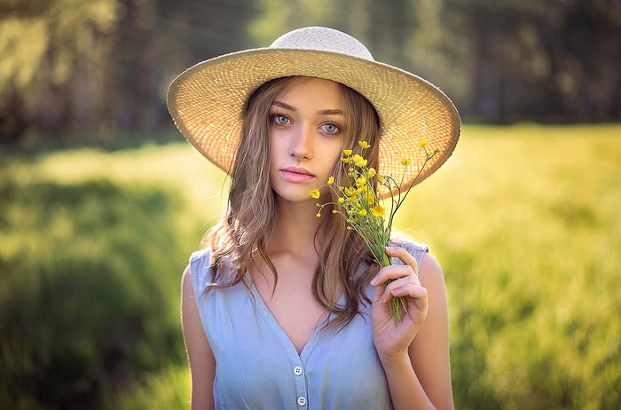 Woman in straw hat holding yellow flowers outdoors