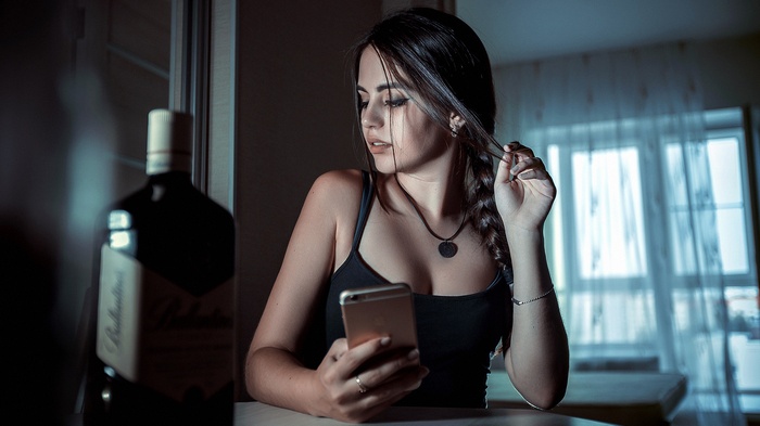 Woman with iPhone and Ballantine's bottle
