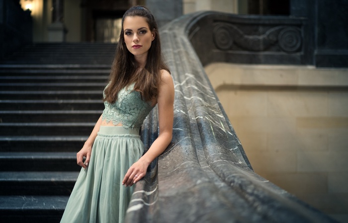 Woman in a green dress on marble stairs