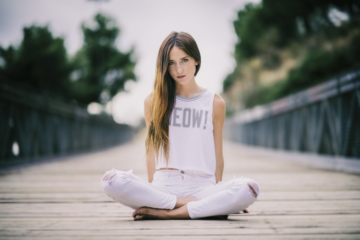 Woman sitting cross-legged on a wooden bridge