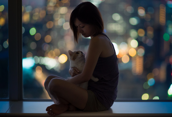 Woman holding a cat with city lights bokeh at night