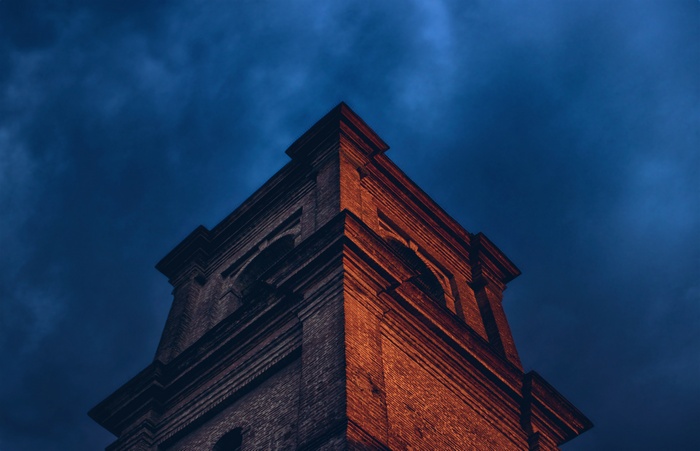 Brick tower against a dark blue cloudy sky