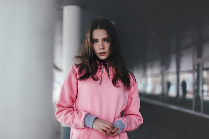 Woman with long brown hair wearing a pink hoodie