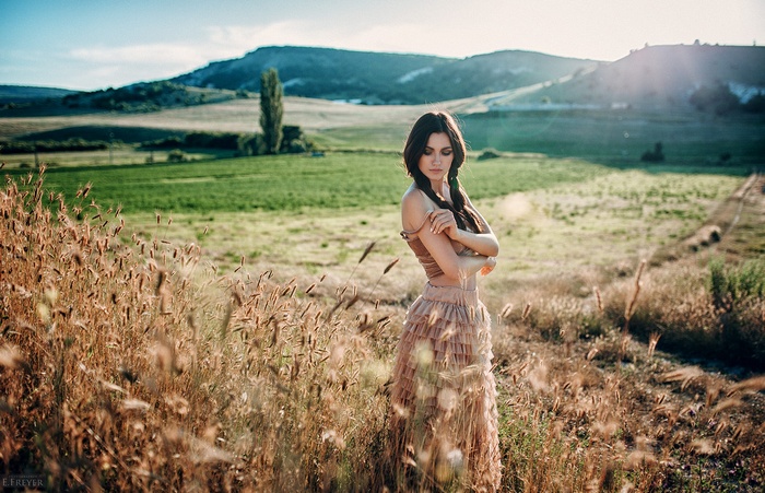 Woman with braids in a field at sunset