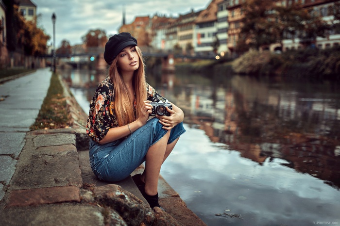 Woman with camera sitting by canal