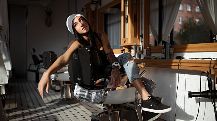 Woman with tattoos sitting in a barber chair