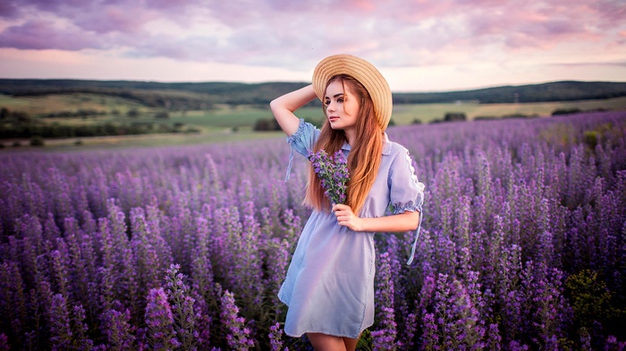 Woman in straw hat holding flowers in lavender field