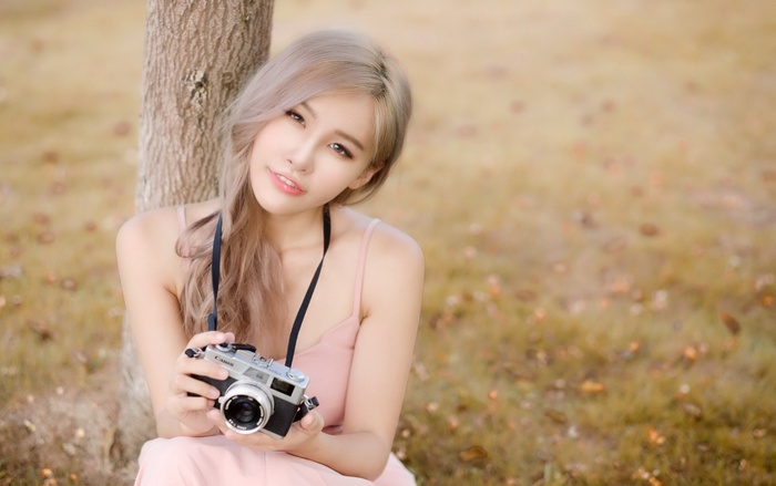 Asian woman holding a vintage camera outdoors