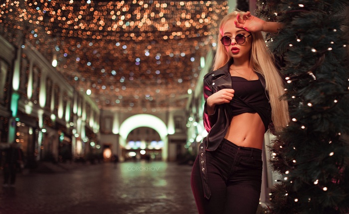 Woman in sunglasses and leather jacket with Christmas lights