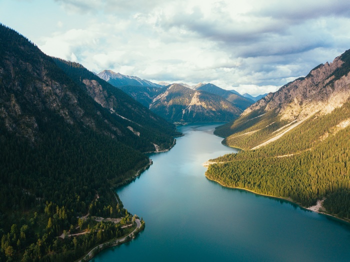 Aerial view of a winding lake between forested mountains