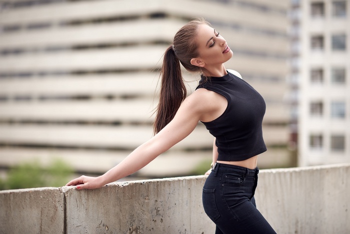 Woman with ponytail wearing black top and jeans outdoors