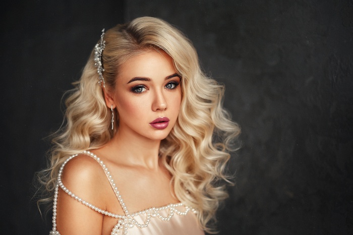 Woman with blonde wavy hair and pearl necklace