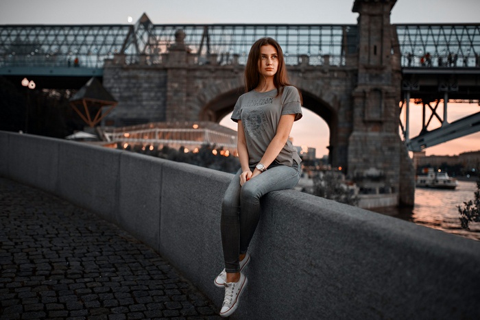 Woman sitting on a wall near a bridge