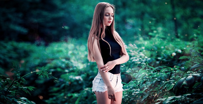 Woman in jean shorts and black top in a forest