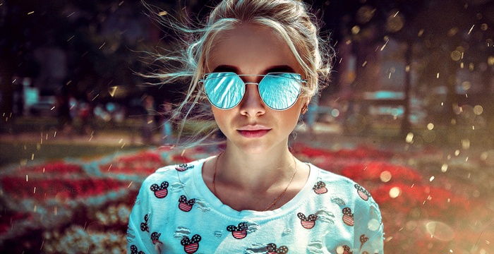 Woman with blonde hair wearing sunglasses and a white shirt