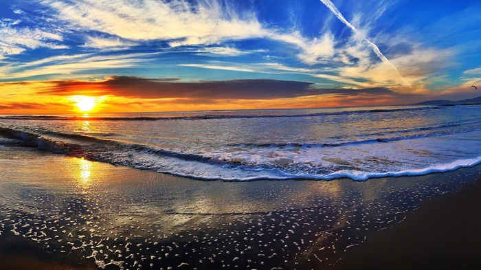 Sunset over the ocean with waves on the beach