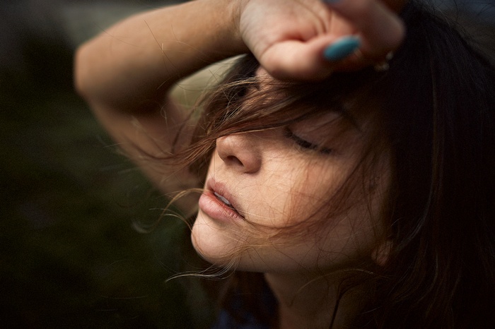 Woman with hand on forehead, hair covering face