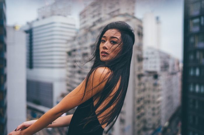 Woman with dark hair in front of city buildings