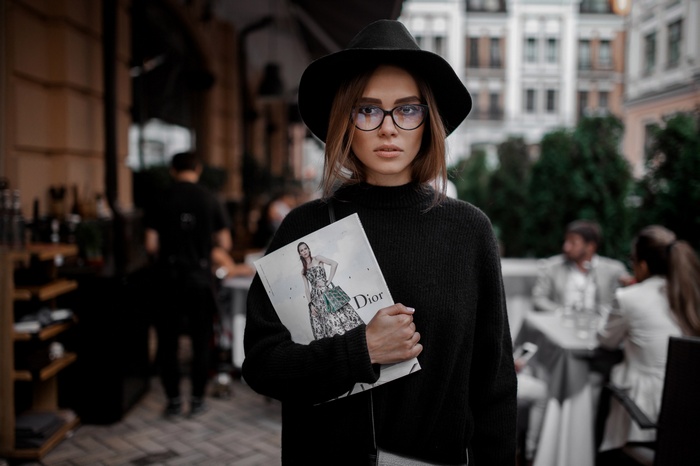 Woman in black hat and sweater holding Dior magazine