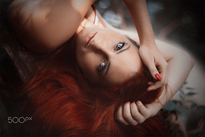 Woman with red hair and blue eyes lying down