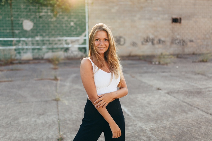 Woman with blonde hair wearing a white top and black pants