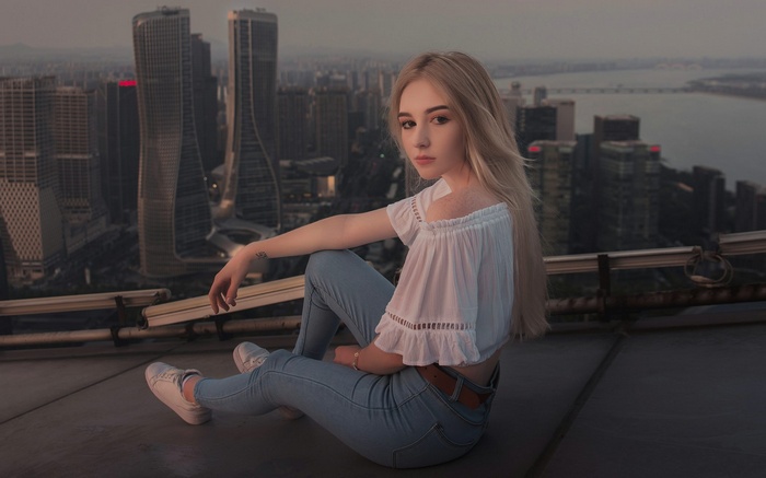 Woman sitting on a rooftop overlooking a city skyline