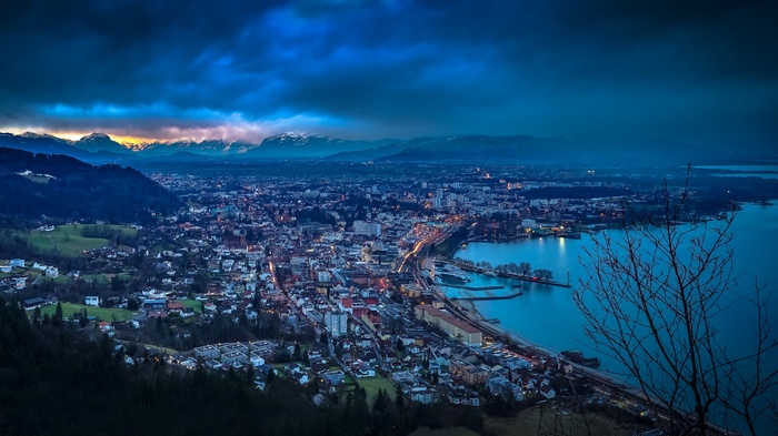Cityscape at dusk with mountains and lake