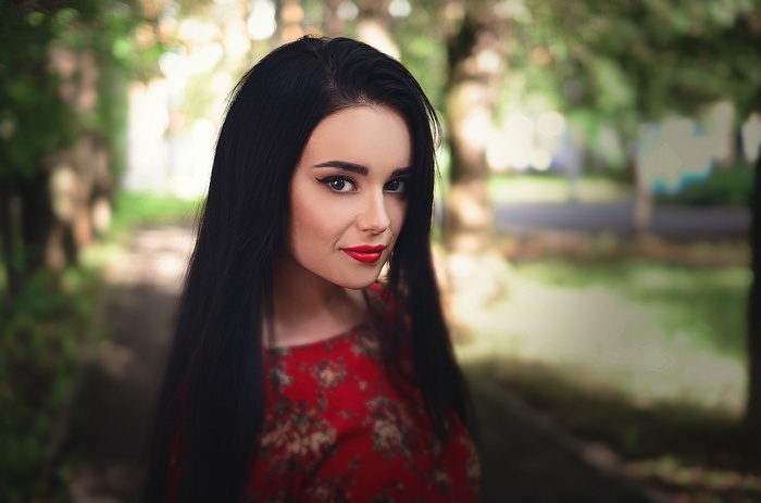 Woman with black hair and red lipstick outdoors