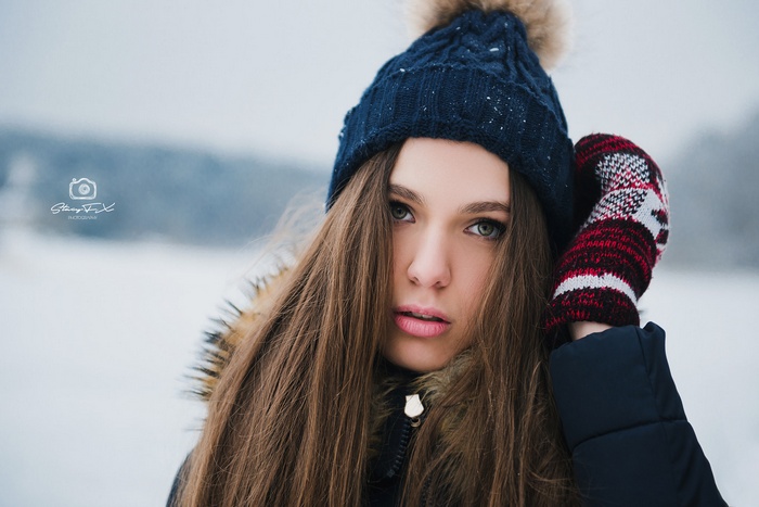 Woman in a blue knitted hat and mittens in the snow