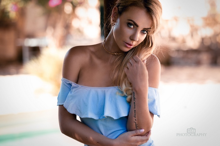 Woman with blue eyes and tattoo in blue dress