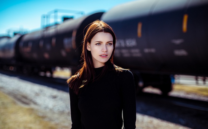 Woman in black clothing standing by a train