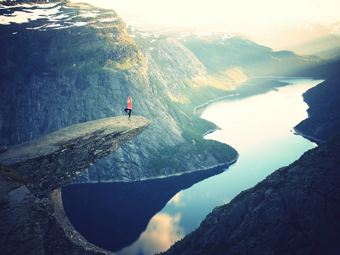 Woman doing yoga on Trolltunga cliff overlooking fjord