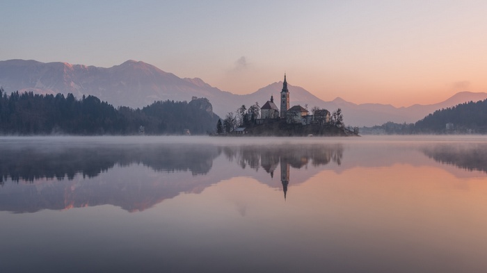Lake Bled island church at dawn with misty reflection
