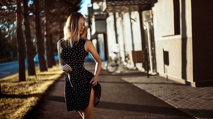 Woman in polka dot dress lifting skirt on sidewalk