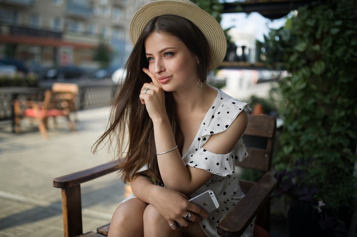 Woman in a straw hat and polka dot dress sitting on a chair