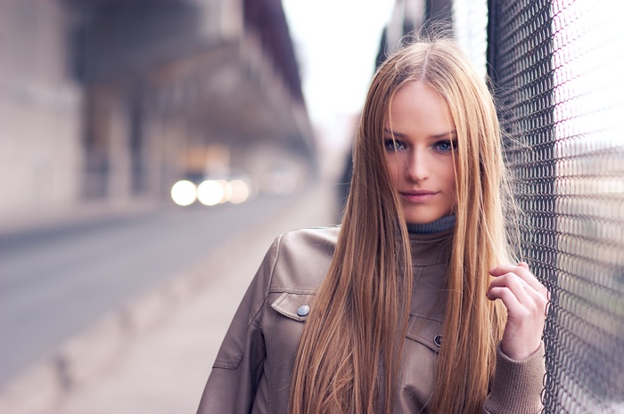 Woman with long blonde hair by a fence
