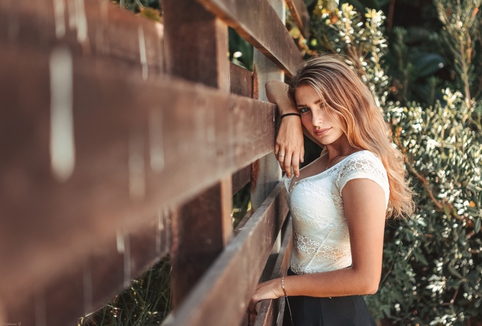 Woman leaning on a wooden fence
