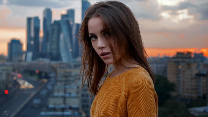 Woman in yellow sweater with Moscow City skyline at sunset
