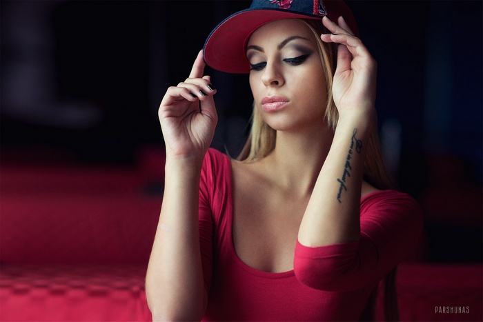 Woman in red shirt and baseball cap with tattoo