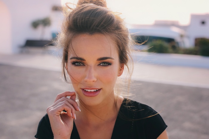 Woman with green eyes and hair in a bun looking at viewer