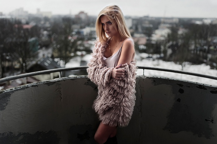 Woman in fluffy coat on a balcony overlooking city