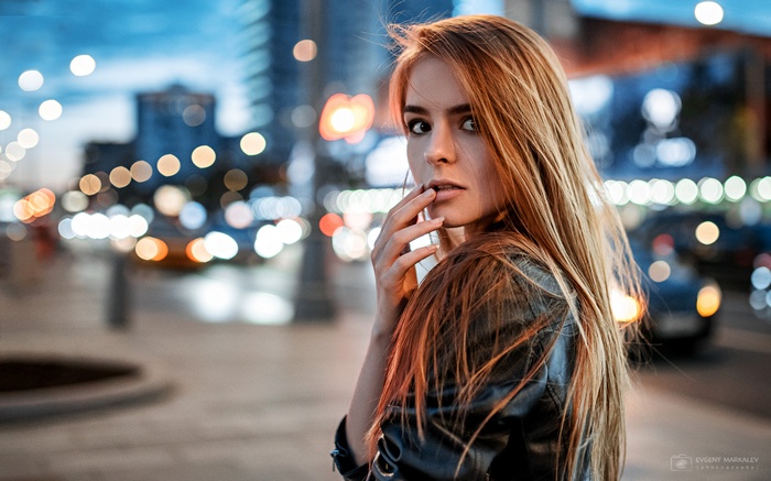 Woman with finger on lips in city at night
