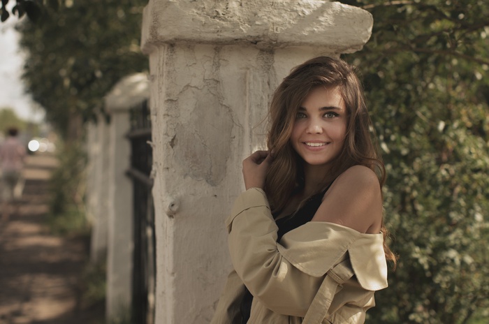 Woman in trench coat smiling outdoors