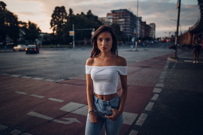 Woman in white off-the-shoulder top and jeans on city street