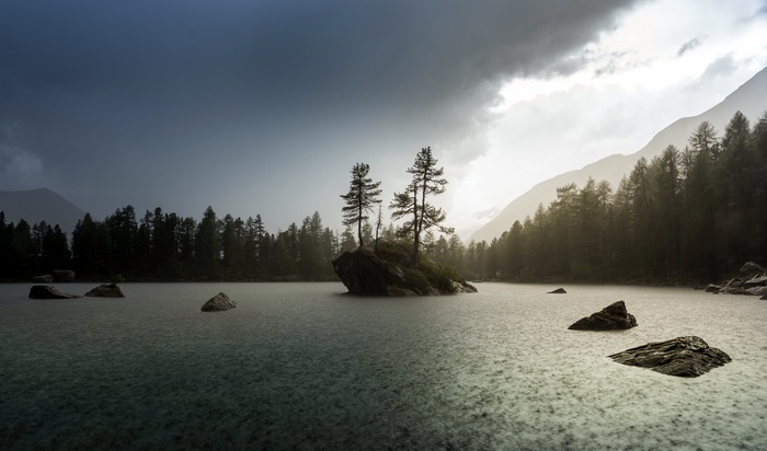 Rainy lake with trees and mountains