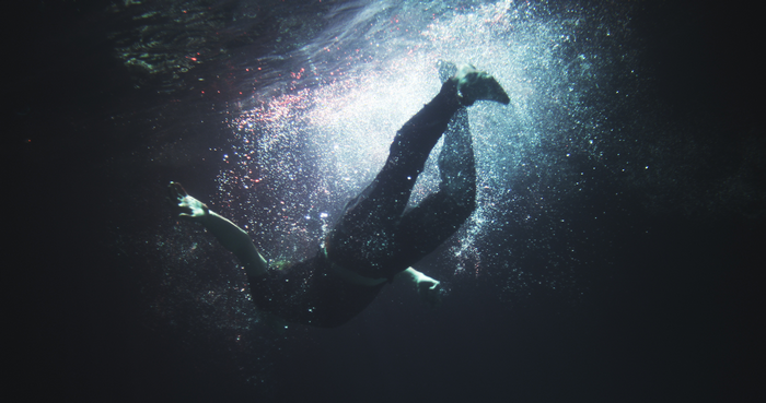 Person diving underwater with bubbles